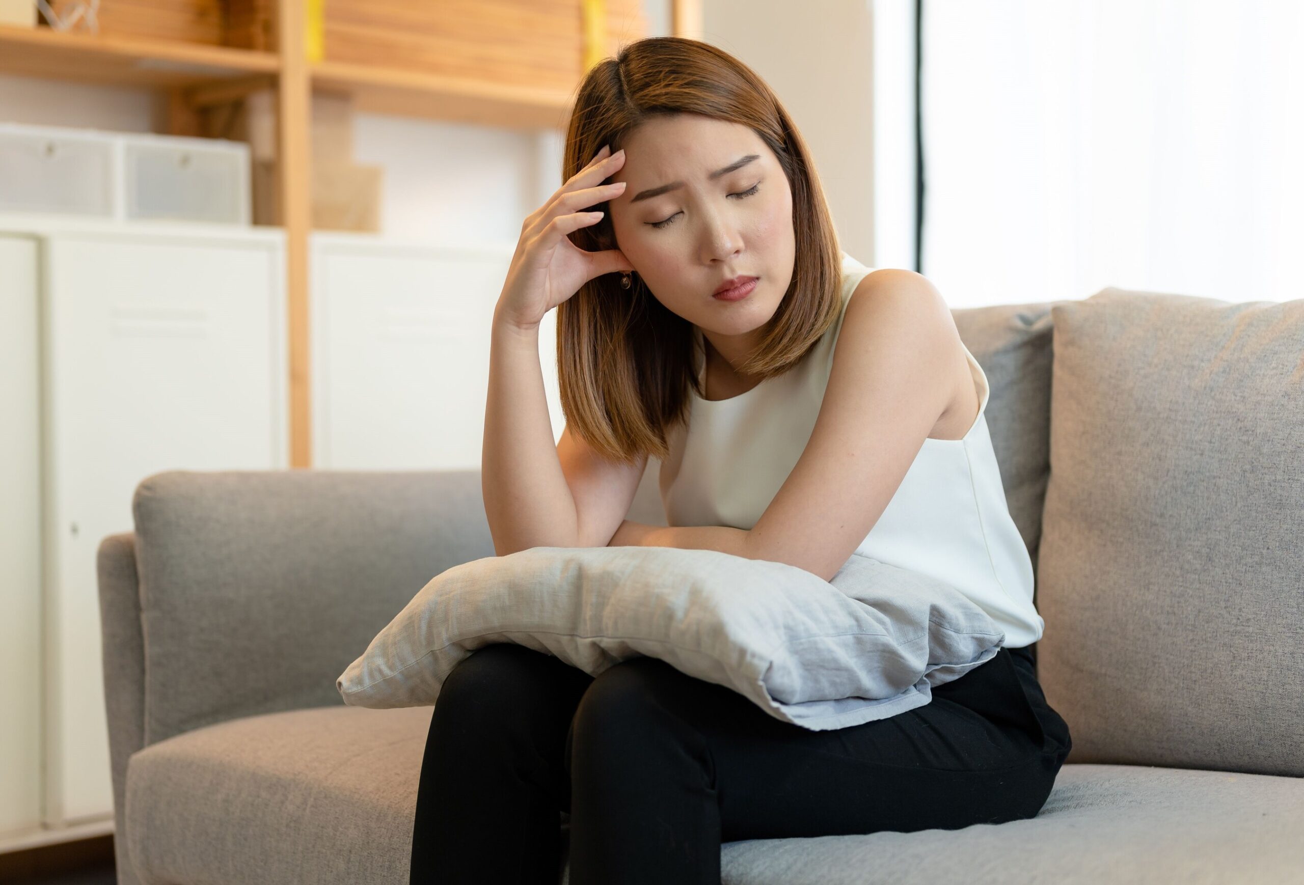 Image A young Asian female feeling depressed and unhappy sitting on a couch at home