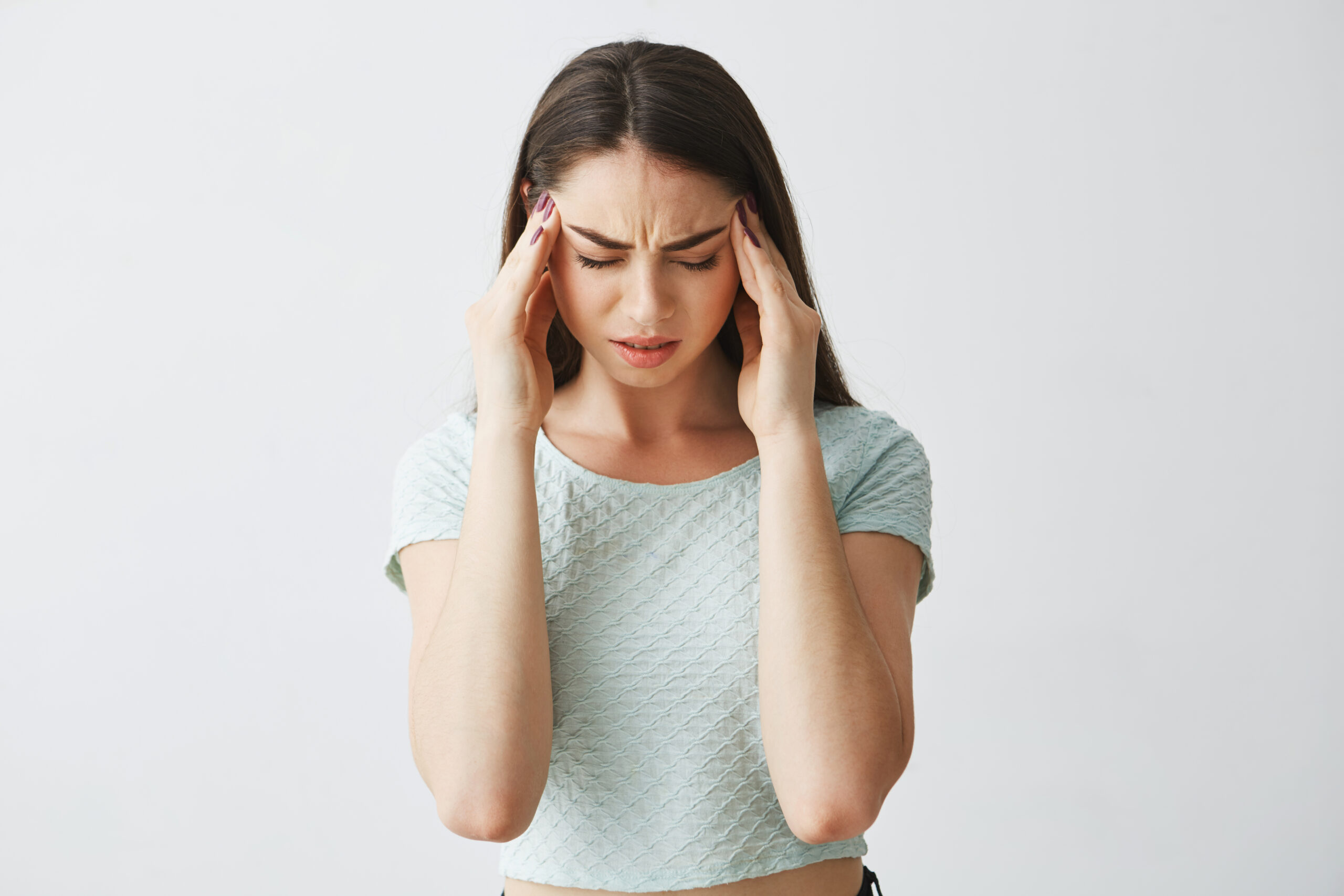 Image Young beautiful brunette girl frowning touching temples. Headache. Isolated on white background.